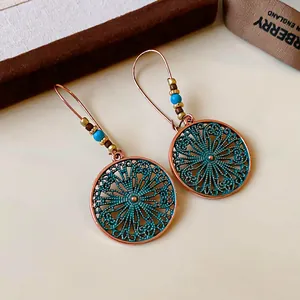 Close-up of bohemian hollow flower earrings with turquoise beads and copper finish.