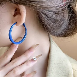 Close-up of vibrant Klein blue hoop earrings showcasing a retro and elegant style