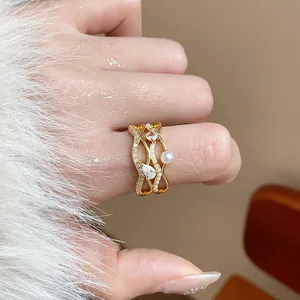 Detailed view of an 18k gold plated wavy ring with pearls and zircons on a finger