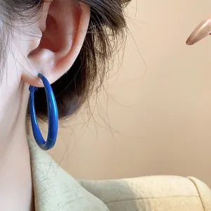 Close-up detail showing a vibrant Klein blue hoop earring worn on a model's ear