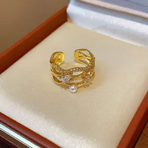 Close-up of a 18k gold-plated wavy ring featuring white pearls and zircon in a gift box
