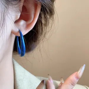 Macro detail of royal blue hoop earrings worn on an ear, vintage minimalist style.