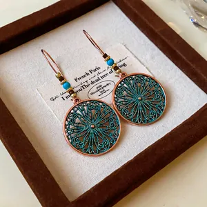 Detail view of vintage-inspired round floral filigree earrings with teal enamel and beads