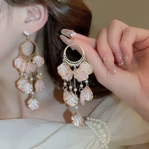 Close-up detail of elegant long dangle earrings with pink shell petals and pearls.