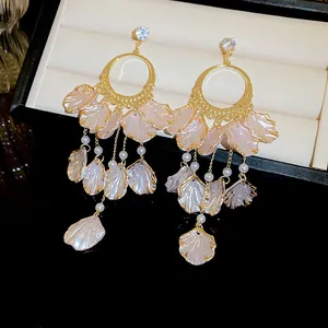 Close-up of elegant gold tassel earrings with pink shell petals and white pearls