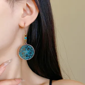 Detailed close-up showing bohemian enamel round flower dangle earrings worn on a model ear.