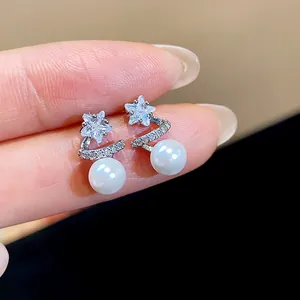 Close-up detail of elegant star-shaped zircon earrings with white pearls in silver finish.