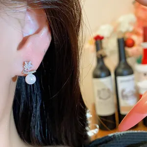 Detailed close-up showing a star-shaped zircon and white pearl stud earring on an ear