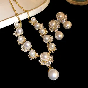 Elegant vintage style gold necklace and earring set featuring pearls and rhinestones