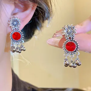 Detailed view of vintage silver floral earrings with red rhinestone centerpiece design.