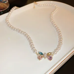 Dettaglio di collana di perle vintage con ciondolo a farfalla in pietre preziose colorate