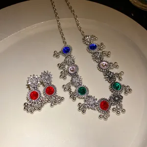 Detailed view of vintage silver necklace and earrings set with colorful rhinestones.