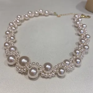 Primer plano de un elegante collar de perlas blancas con cadena dorada ajustable