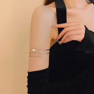Close-up of a minimalist silver wrap-around arm cuff bracelet worn on the upper arm