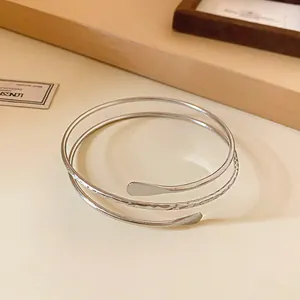 Detail view of a minimalist silver spiral open bangle with unique hammered texture