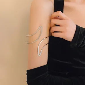 Detail of a minimalist silver open arm cuff bracelet worn on the model's upper arm