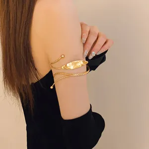 Detailed view of elegant gold leaf-shaped upper arm cuff on model arm