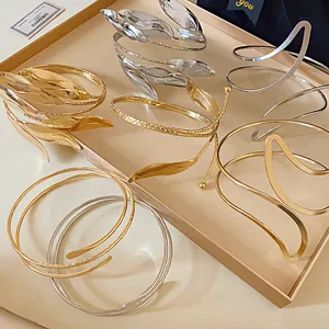 Macro view of assorted gold and silver leaf-shaped open cuff bracelets on a tray