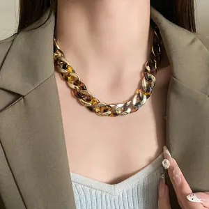 Close-up of a chunky chain necklace with gold and tortoiseshell links on a model