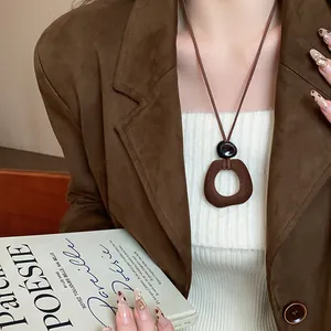 Collana con ciondolo geometrico in resina marrone floccata su un top bianco chic