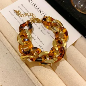 Detailed view of a retro chunky tortoiseshell and golden metal chain bracelet on a white card