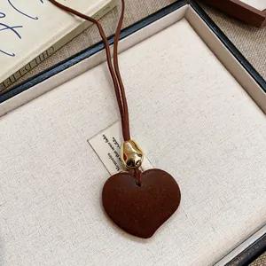 Dettaglio collana con pendente a cuore floccato marrone e perla dorata