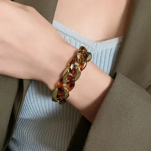 Detailed close-up of a chunky tortoiseshell patterned and gold chain bracelet on a wrist