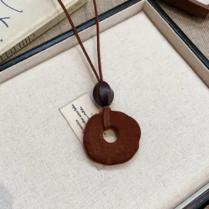 Primo piano della collana con pendente in resina floccata marrone su lino grezzo
