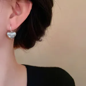 Eleganti orecchini a cuore in argento spazzolato con strass indossati da una modella