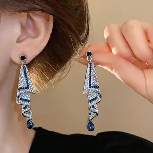 Close-up of elegant silver drop earrings with blue rhinestones and crystal inlay