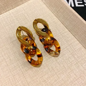 Close-up of chunky chain earrings with gold metal and tortoiseshell resin links