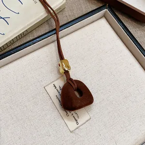 Primo piano di una collana con ciondolo geometrico in resina floccata in tonalità marrone