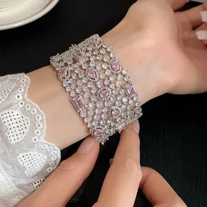 Vista macro dettagliata di un ampio bracciale rigido geometrico con pietre di zirconi rosa.