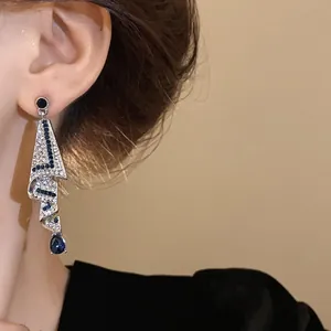 Detailed close-up view of elegant silver dangling earrings with blue teardrop rhinestones