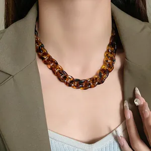 Close-up of a chunky tortoiseshell chain necklace worn with an olive blazer.