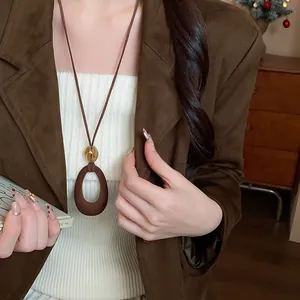 Dettaglio ravvicinato di un elegante ciondolo in resina floccata marrone su una modella.