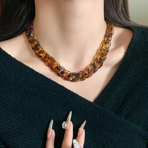 Close-up of tortoiseshell chunky chain necklace worn on a neck with black sweater.