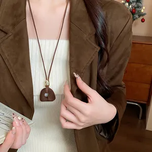Dettaglio di una collana con pendente geometrico in resina floccata per l'autunno.