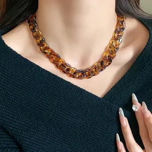 Close-up detail of a stylish chunky tortoiseshell resin chain necklace worn by a model