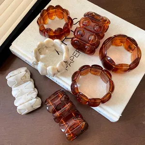 Close-up detail of vintage marbled acrylic stretch bracelets in amber and cream tones