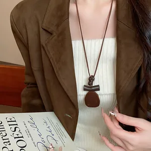 Dettaglio ravvicinato di una collana con ciondolo geometrico in resina floccata su blazer.