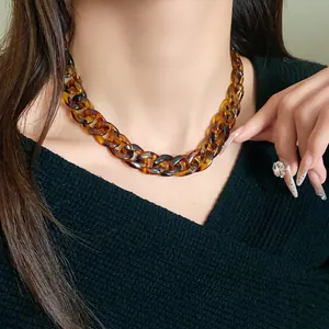 Close-up of tortoiseshell acrylic chunky chain necklace on model.