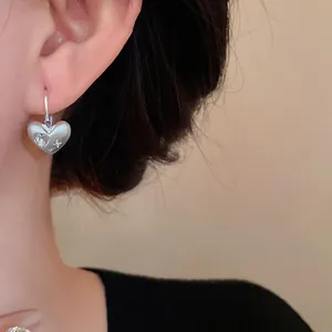 Primo piano di un orecchino a cuore in argento spazzolato con cristalli su un modello