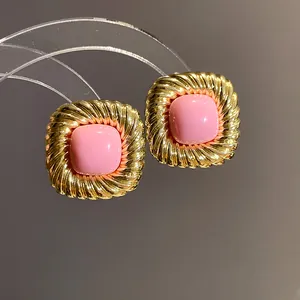 Dettaglio di orecchini quadrati vintage con cornice dorata e inserto centrale rosa