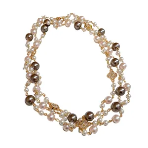 Collana di perle multifilo con ciondoli a fiore in strass e catena lunga dorata.