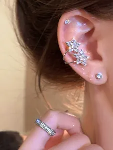 Close-up detail of a sparkling zircon star ear cuff and a matching eternity ring on model.