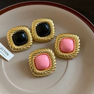 Dettaglio di orecchini vintage quadrati con trama dorata intrecciata e pietre colorate lucide