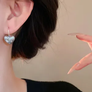 Primo piano di orecchini a cerchio a cuore spazzolato con strass scintillanti