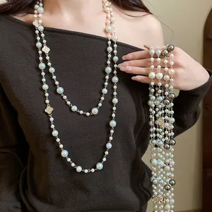 Dettaglio di lunga collana di perle di lusso con ciondoli a quadrifoglio con diamanti
