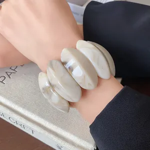 Detailed close-up of a marbled resin oval elastic bracelet worn on a woman's wrist